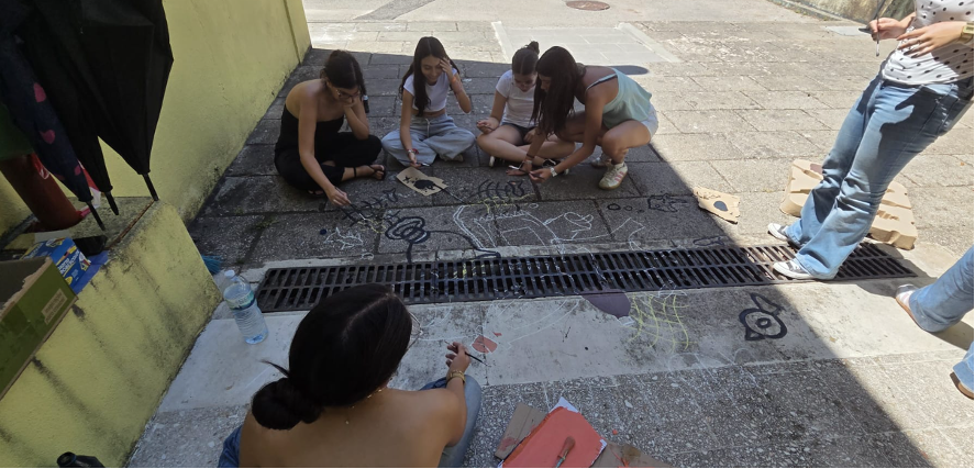 Alunos a desenhar na sarjeta.