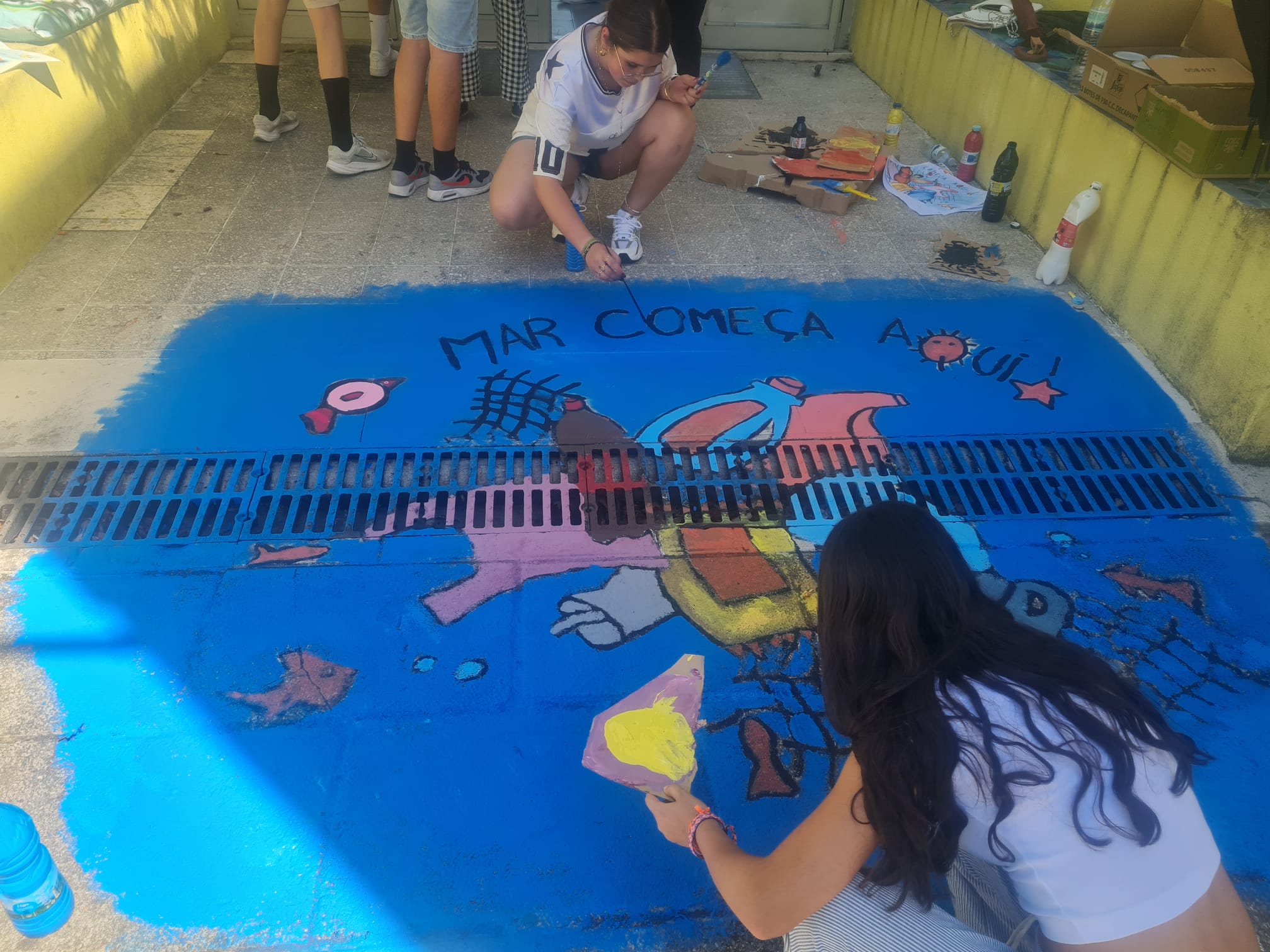 Alunos a pintar a sarjeta.