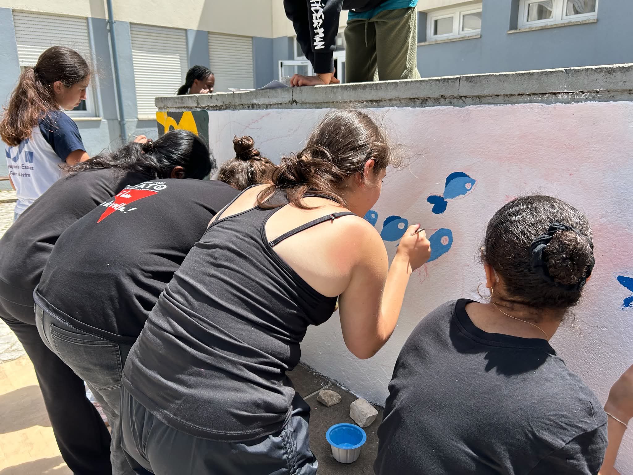 Início do desenho a giz e da pintura mural sobre a parede previamente preparada com primário, mostrando o trabalho colaborativo desenvolvido pela turma.