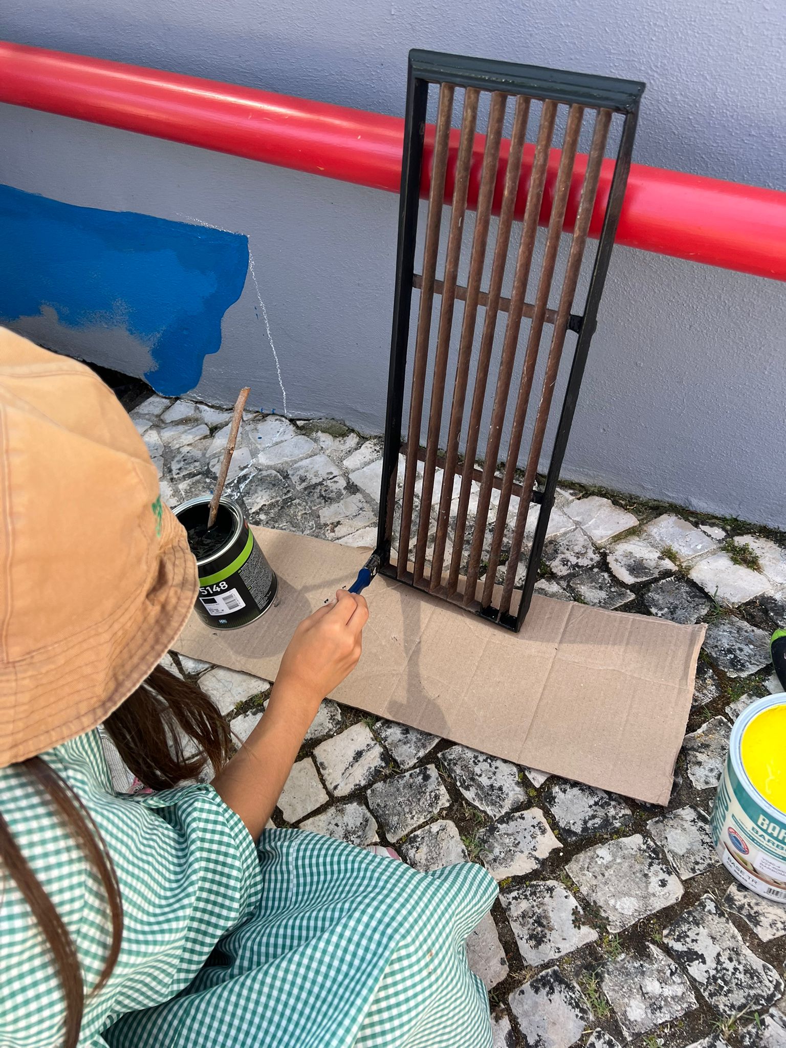 Aluno a pintar a grelha da sarjeta